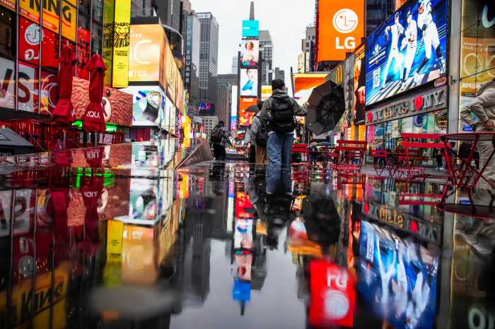 A person walks through wind and rain during a nor'easter storm at Times Square in New York City, U.S., October 13, 2025.