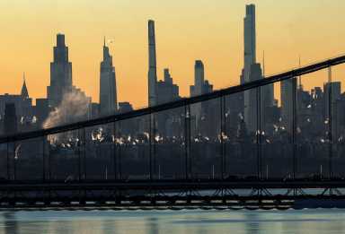 Steam rises from buildings as the sun rises over Manhattan beyond the George Washington Bridge and the Hudson River, as a blast of Arctic air gripped much of the central and eastern portions of the U.S, in New York City, U.S., December 9, 2025.