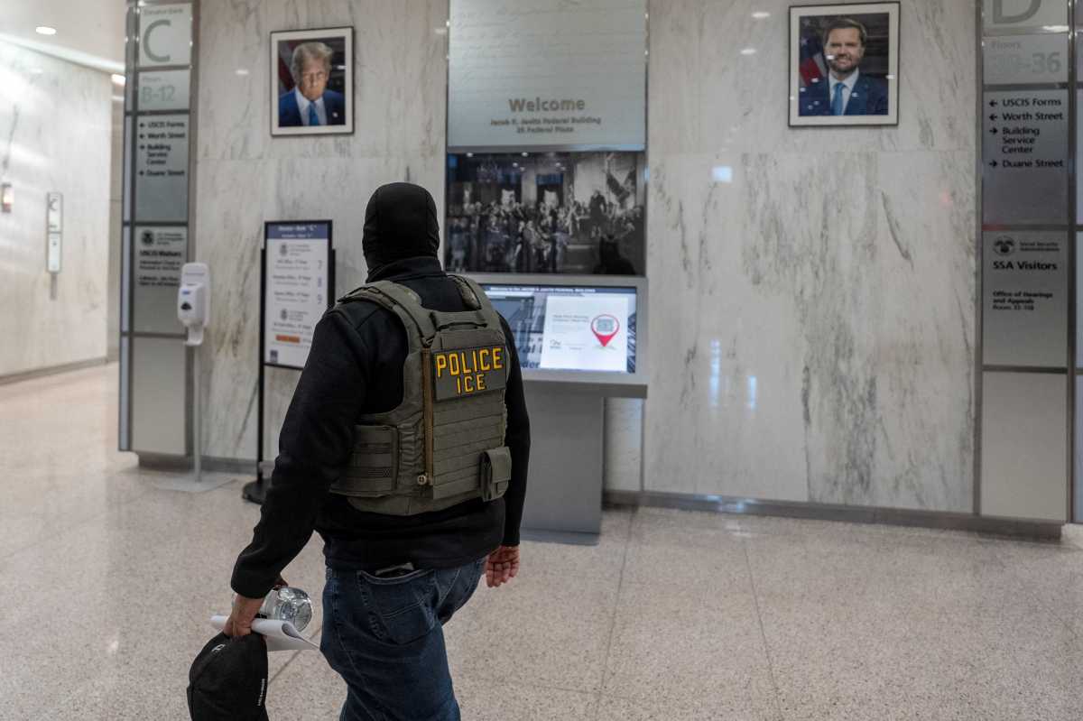 An Immigration Customs Enforcement (ICE) officer walks past portraits of US President Donald Trump and Vice President JD Vance at US immigration court in Manhattan, New York City, US, December 9, 2025.