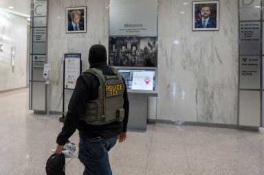 An Immigration Customs Enforcement (ICE) officer walks past portraits of US President Donald Trump and Vice President JD Vance at US immigration court in Manhattan, New York City, US, December 9, 2025.