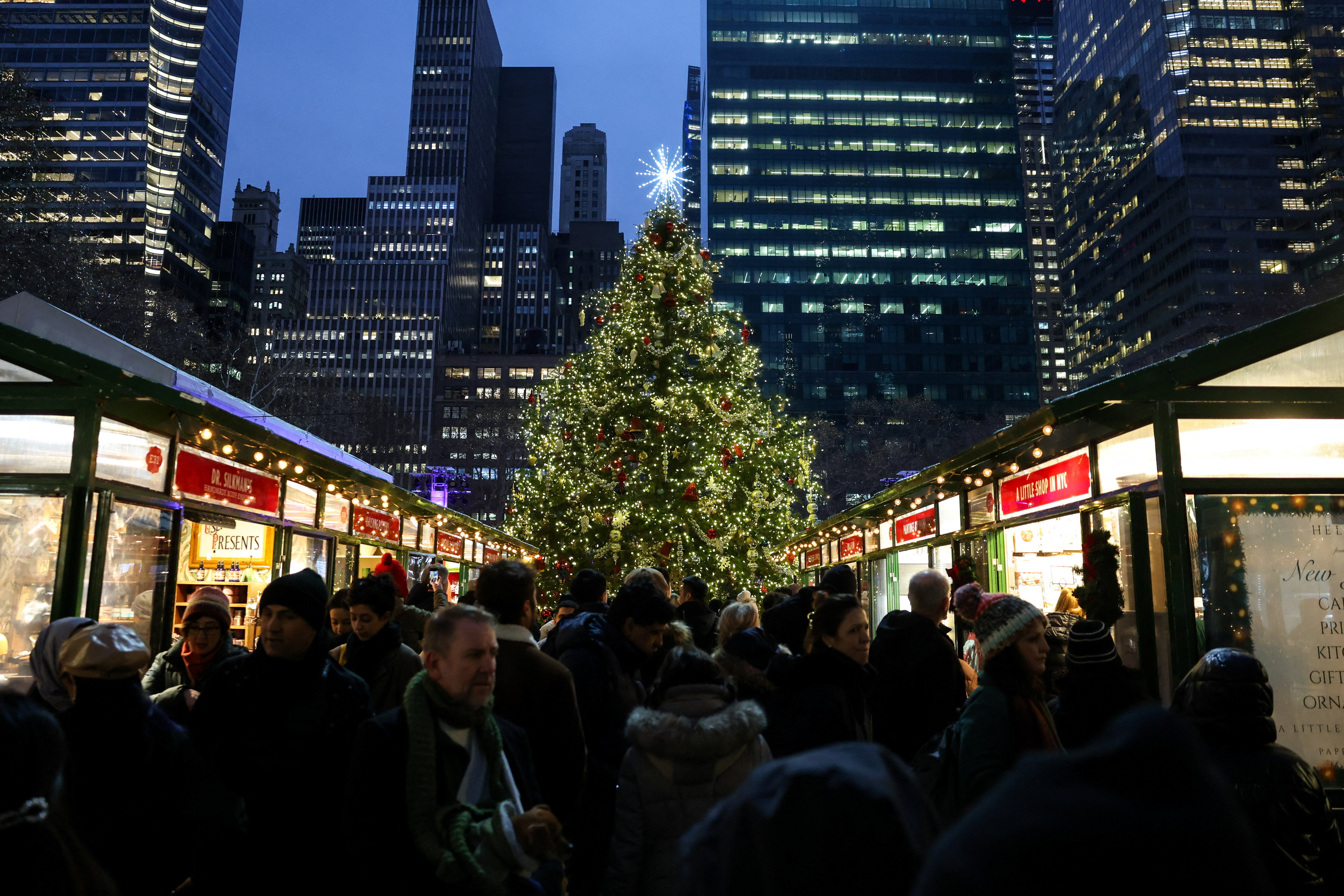 People walk near a Christmas tree at Bryant Park's holiday market in New York City, U.S. December 23, 2025.