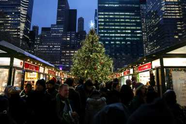 People walk near a Christmas tree at Bryant Park's holiday market in New York City, U.S. December 23, 2025.