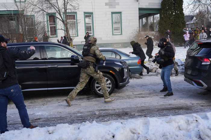 A federal agent runs towards protesters trying to block vehicles from leaving the scene after a driver of a vehicle was shot in Minneapolis, Minnesota, U.S., January 7, 2026.
