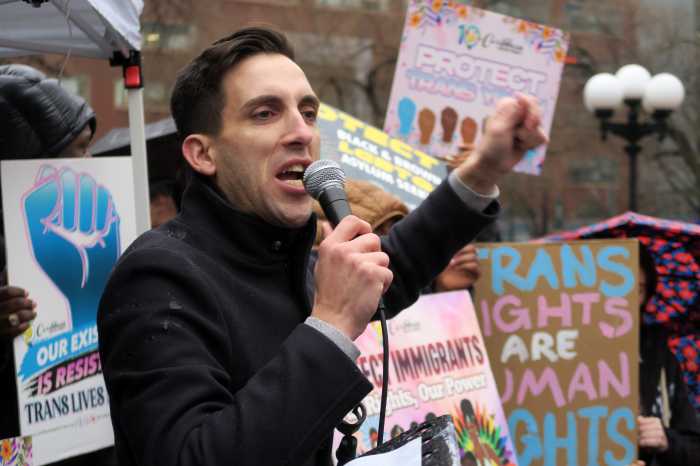 Marti Gould Cummings, surrounded by signs expressing support for trans youth, speaks to the crowd.