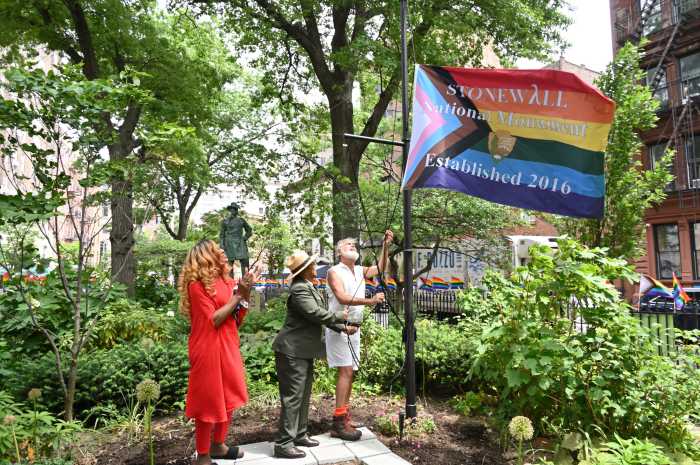 Miss Simone (left) watches Shirley McKinney and Steven Love Menendez lift the Rainbow Flag up into the air at Christopher Park in 2022 — back when the Biden administration allowed the flag to go up, complete with black and brown stripes and the colors of the Trans Flag.