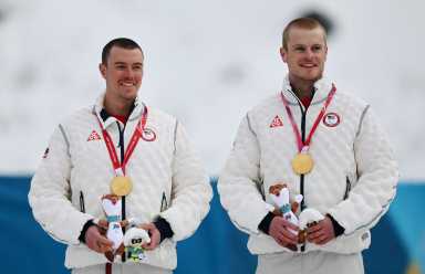 Milano Cortina 2026 Paralympics - Para Cross-Country Skiing - Men's Sprint Classic Vision Impaired Victory Ceremony - Tesero Cross-Country Skiing Stadium, Lago, Italy - March 10, 2026. Gold medallists Jake Adicoff of United States and guide Peter Wolter of United States celebrate on the podium.