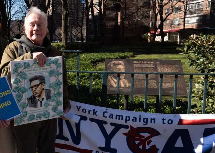Walter Naegle holds a photo of his late partner, Bayard Rustin, near a banner for the New York Campaign to Abolish Nuclear Weapons.