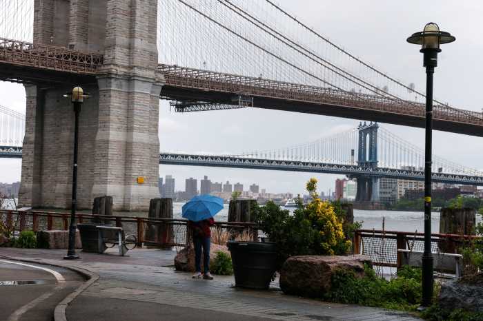 A woman stands with an umbrella near the Brooklyn Bridge during rainy weather in New York City, U.S., May 21, 2026.