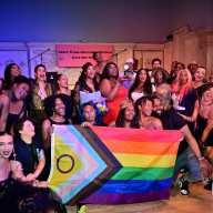 Qween Jean holds her Tony award while surrounded by attendees at the "Broadway is Trans" fundraiser.