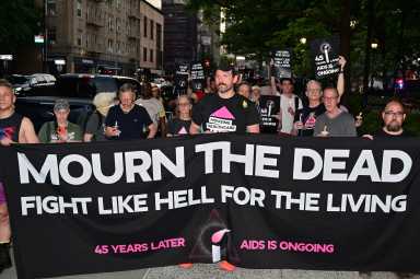 Community members carry a banner calling to mourn the dead and fight for the living.