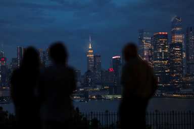 People watch clouds passing over the Empire State Building and New York skyline during a rainstorm, as seen from Weehawken, New Jersey, U.S., June 22, 2026.