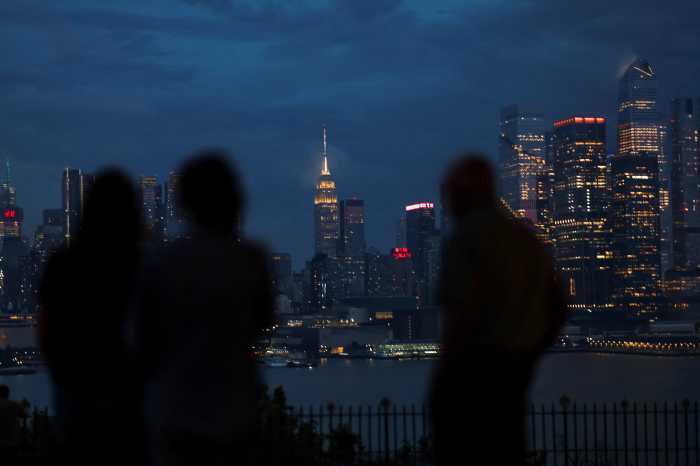 People watch clouds passing over the Empire State Building and New York skyline during a rainstorm, as seen from Weehawken, New Jersey, U.S., June 22, 2026.