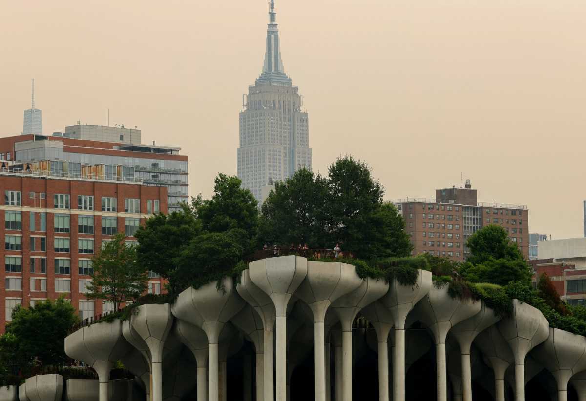 People stand at the top of 'Little Island' park along the Hudson River on Manhattan's west side with the Empire State Building behind seen through a cover of wildfire smoke in New York City, U.S., July 16, 2026.