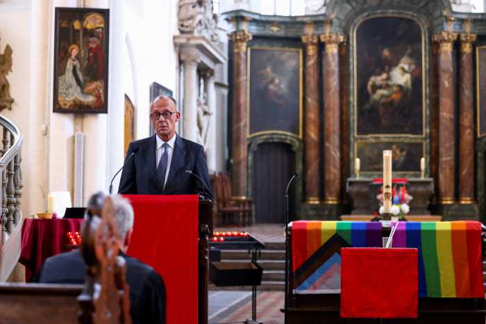 German Chancellor Friedrich Merz speaks next to an altar draped in rainbow flags during a memorial service at St. Mary's Church after a deadly incident in which a vehicle crashed into a crowd near Berlin's annual Christopher Street Day Pride parade on Saturday evening, leaving multiple people injured and the parade called off, in Berlin, Germany, July 26, 2026. 