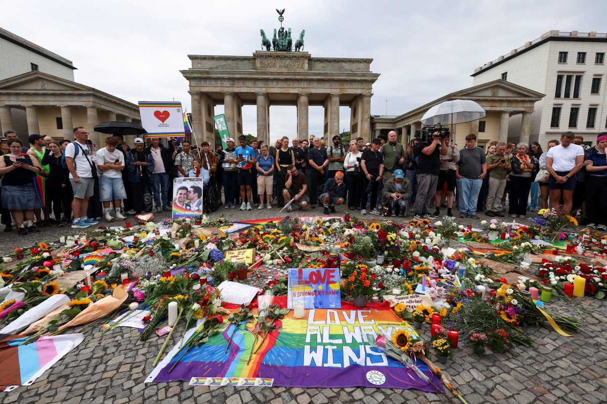 People gather around flowers, mementos, and candles in Berlin, Germany on July 26 at the Brandenburg Gate, after a deadly incident in which a vehicle crashed into a crowd near Berlin's annual Christopher Street Day Pride parade on the evening of July 25.