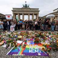 People gather around flowers, mementos, and candles in Berlin, Germany on July 26 at the Brandenburg Gate, after a deadly incident in which a vehicle crashed into a crowd near Berlin's annual Christopher Street Day Pride parade on the evening of July 25.