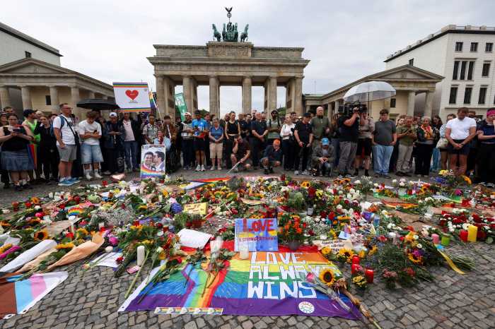 People gather around flowers, mementos, and candles in Berlin, Germany on July 26 at the Brandenburg Gate, after a deadly incident in which a vehicle crashed into a crowd near Berlin's annual Christopher Street Day Pride parade on the evening of July 25.